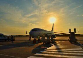 a small commercial passenger jet parked on an airport runway surrounded by airport employees